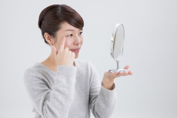鏡で目元を見る女性