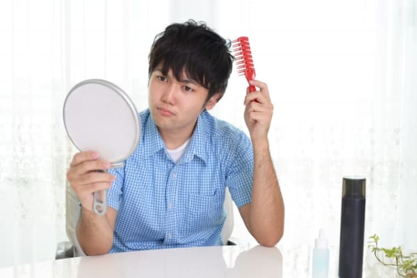 鏡を見ながら髪をとかす男性