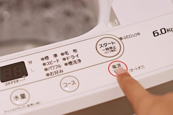 洗濯機のボタンを押す