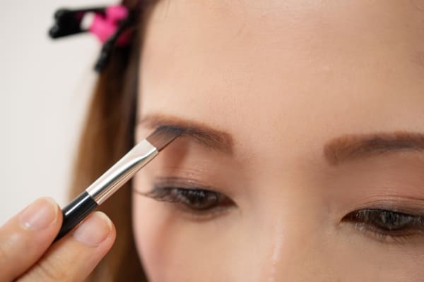 アイブロウパウダーで眉毛を描く女性