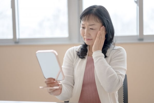 鏡を見て悩む50代女性