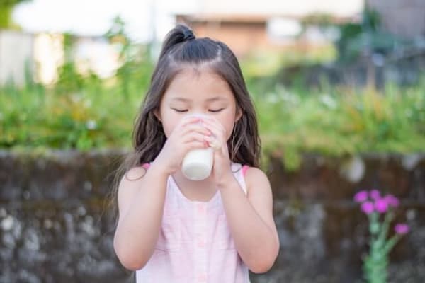 外で牛乳を飲む女の子