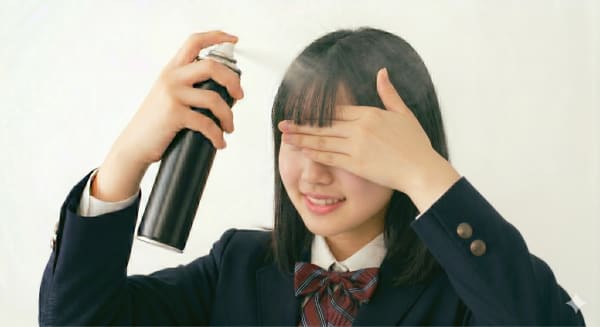 短めの前髪にヘアスプレーをかける女子高校生