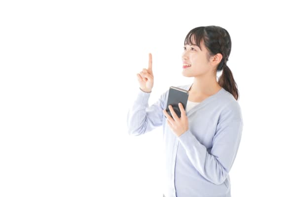 スマホ片手に指を指す女性