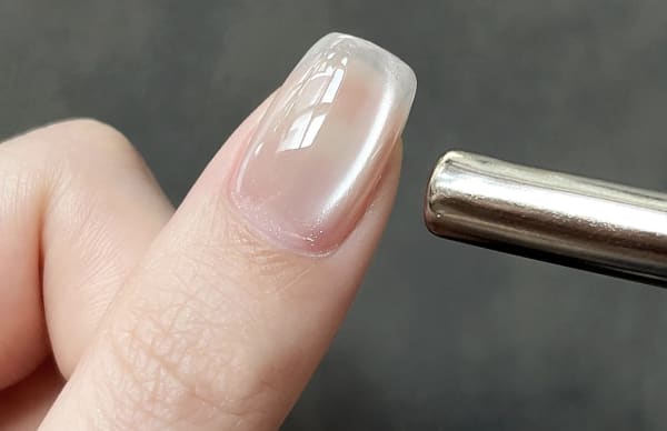 マグネットジェルを塗布した爪に磁石を当てている様子