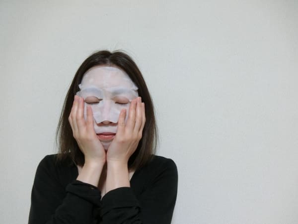 シートマスクをしている顔を手で覆う女性