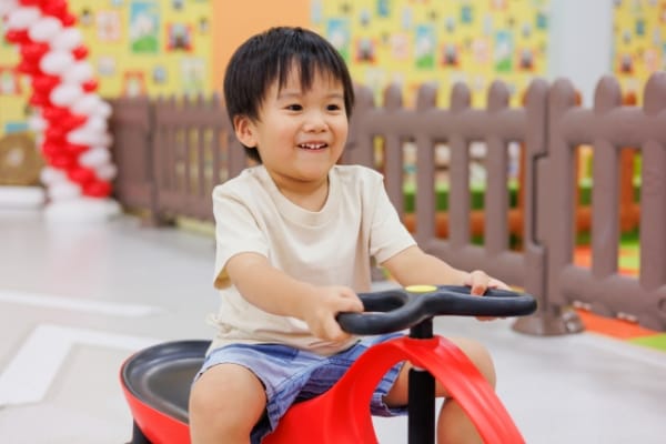 車のおもちゃに乗って遊ぶ幼児